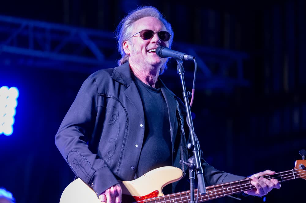 Terry McBride of McBride and the Ride at the microphone with his bass under blue stage light.
