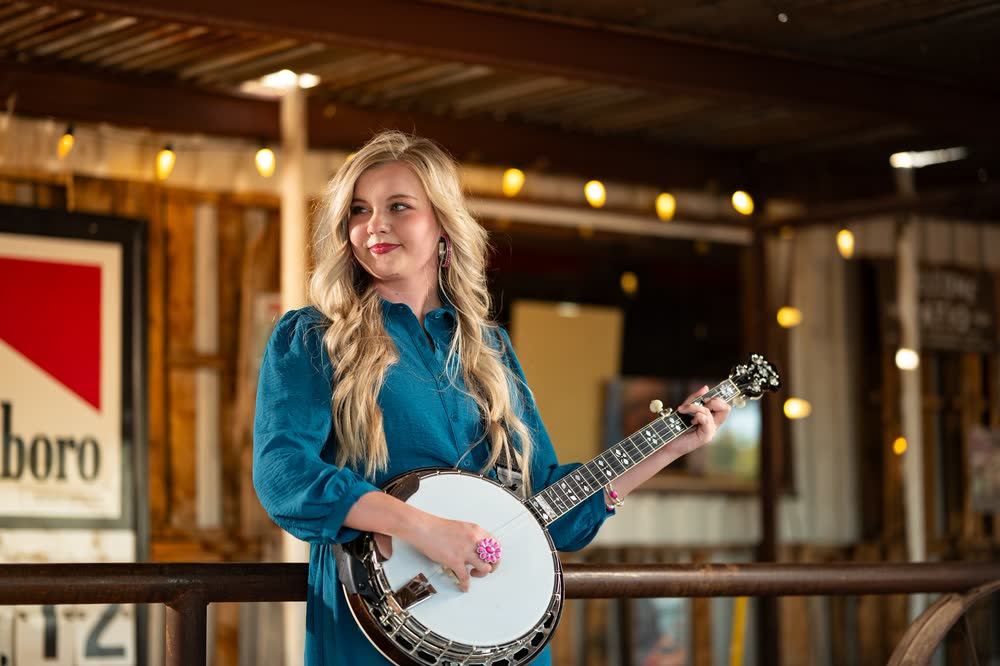 Hadlie Jo with her banjo under the porch string lights at The Coyote Store.