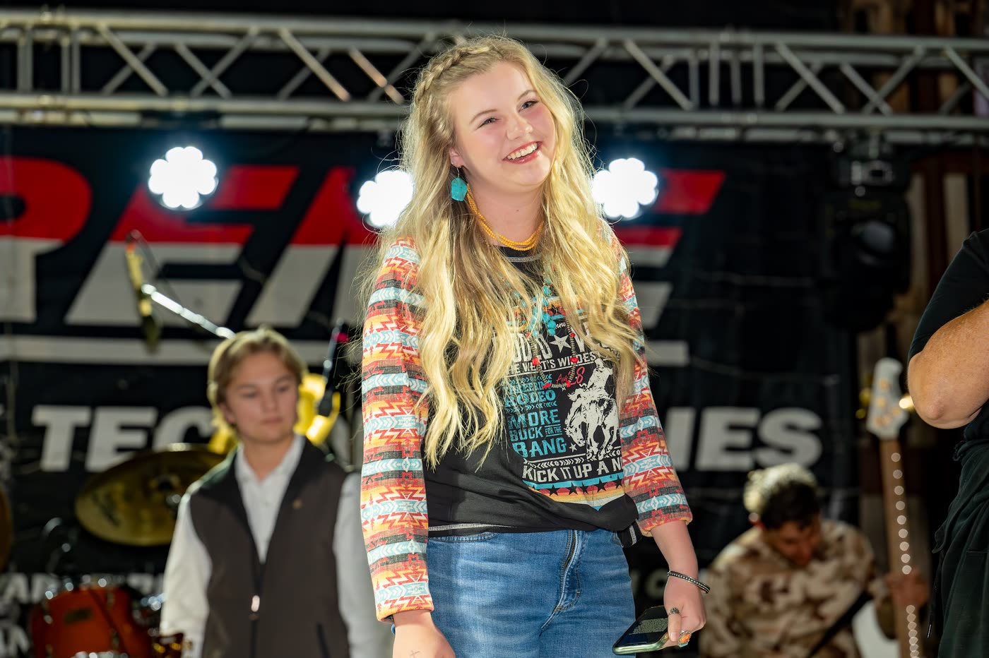 Hadlie Jo performing on the Coyote Store stage, arms wide, band behind her.