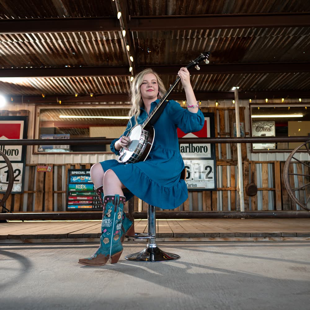 Hadlie Jo standing at a microphone in front of The Coyote Store.